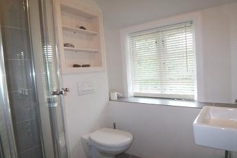 Das moderne Duschbad mit walk in Dusche, Handtuchwrmer und  Fenster ist hell gefliet und wirkt einladend.