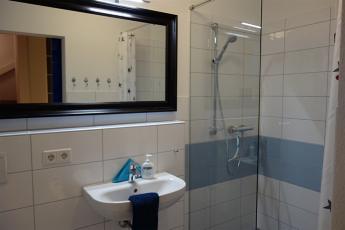 ... ein Duschbad mit großer, bodengleicher Duschkabine, Handwaschbecken und Toilette